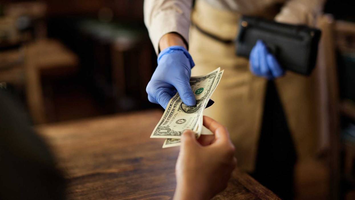 Someone handing over cash to a server at restaurant