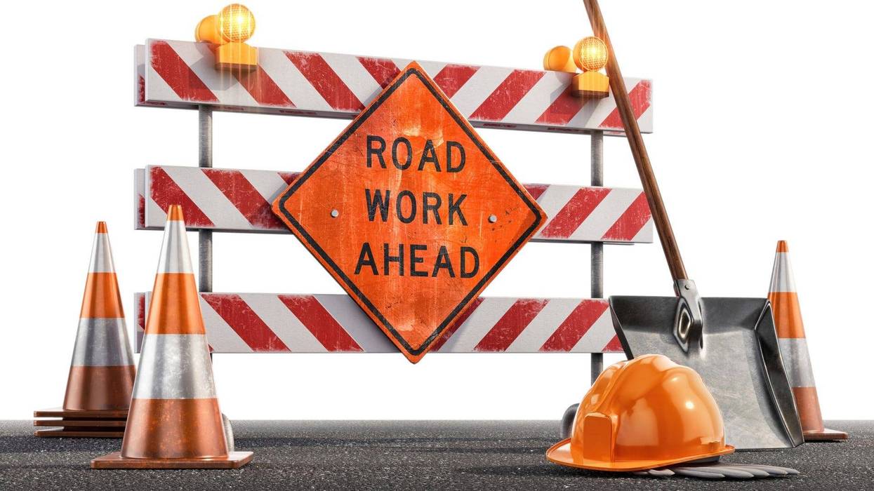 Сonstruction site with a Road Work Ahead sign, traffic cones, hard hat, shovel against a white background. - stock photo