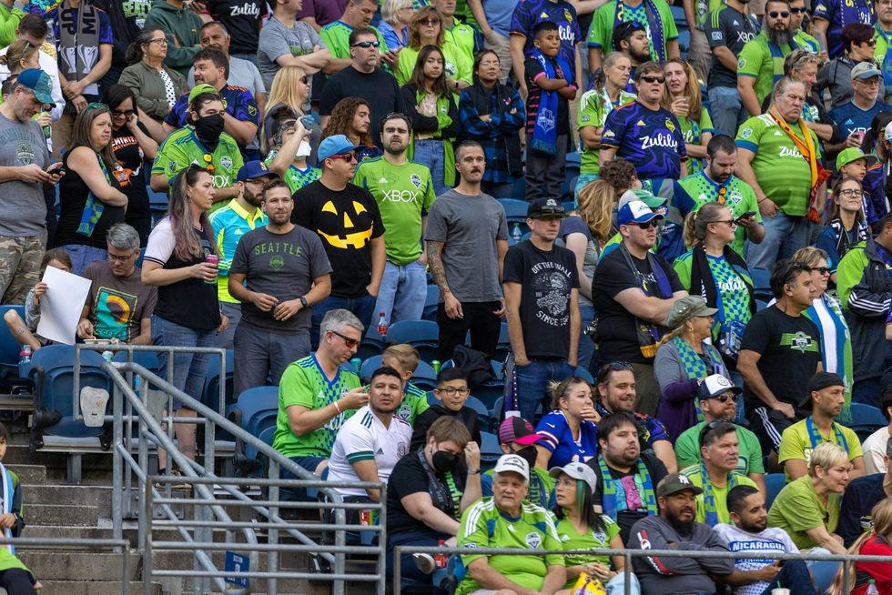 Sounders FC fans including one man in black shirt with bright orange jack-o-lantern pattern printed