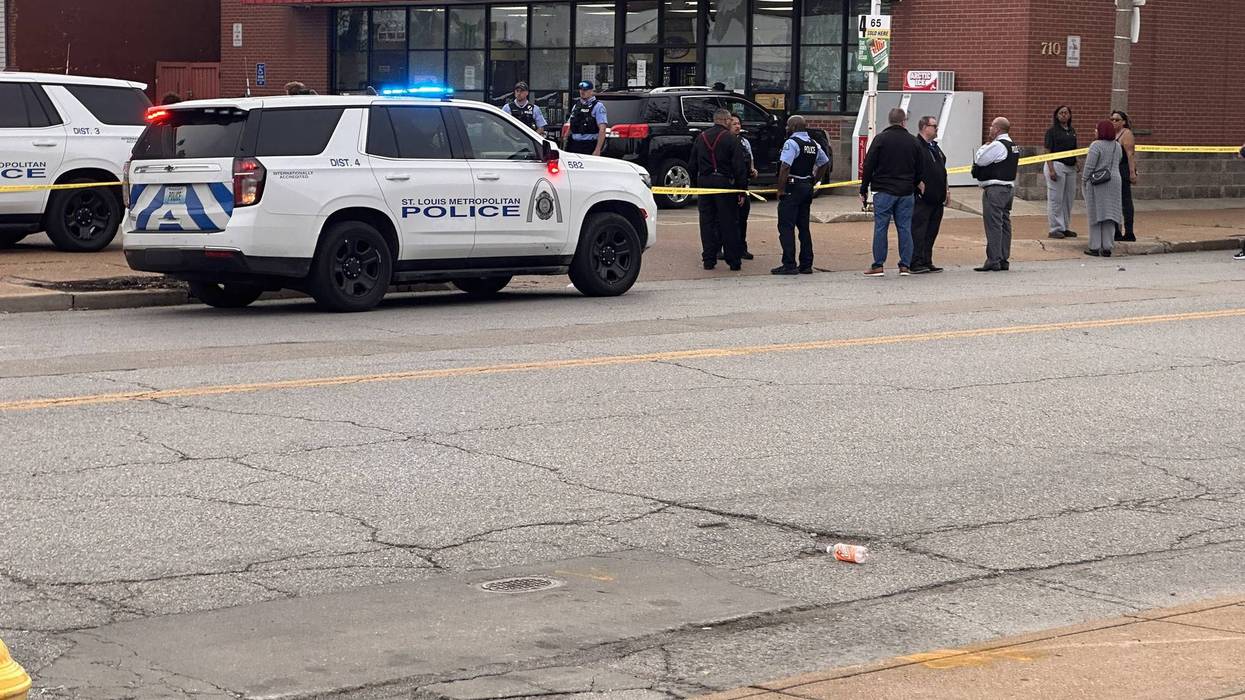 St. Louis police cars, officers, and civilians behind caution tape outside an Express store.