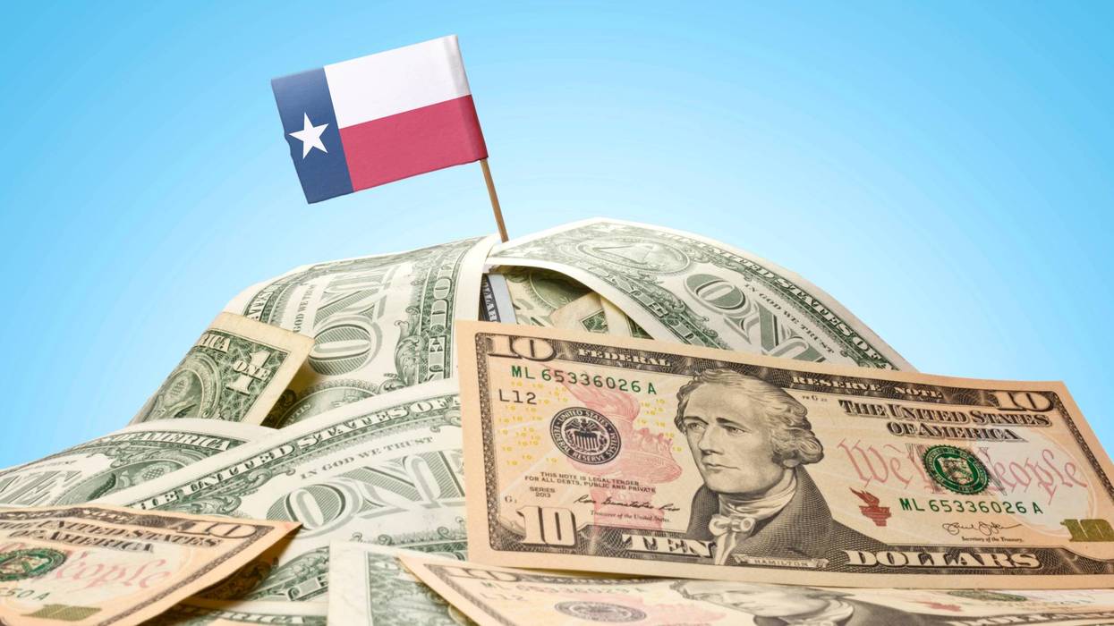 Stacks of money with the Texas State Flag planted at the top