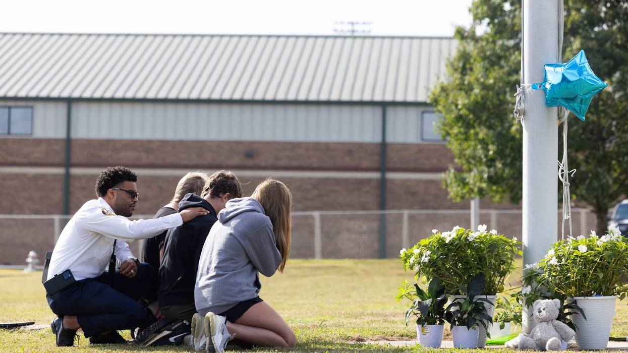State of Georgia Chaplain Ronald Clark consoles students as they kneel in front of a makeshift memorial at Apalachee High School on Sept. 5, 2024, in Winder, Georgia. Two students and two teachers were shot and killed at the school.