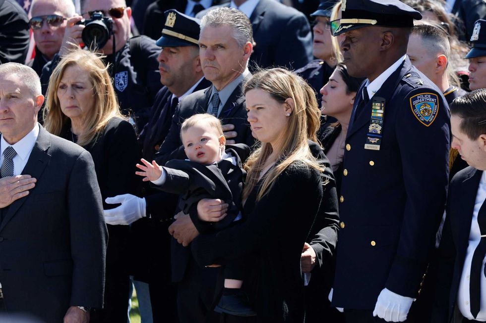 Stephanie Diller, the widow of NYPD officer Jonathan Diller, carries her son Ryan at the funeral of her husband at St. Rose of Lima R.C. Church on March 30, 2024 in Massapequa, New York