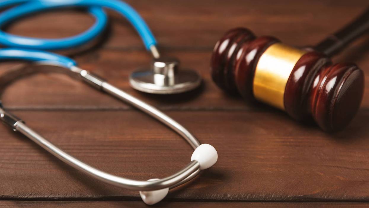 Stethoscope and gavel on dark wood, symbolizing medicine and law.