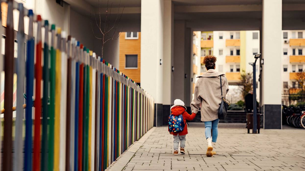 stock image of a woman holding a baby's hand as they walk away from the camera