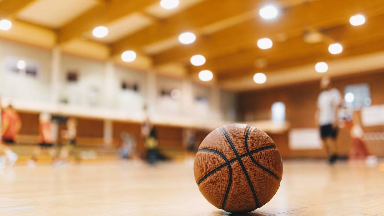 Stock image of basketball on court with players in background