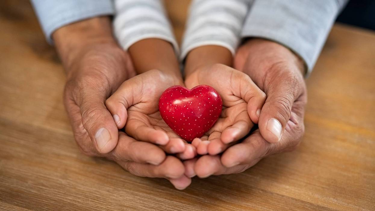 Stock image of child and parent's hands holding heart