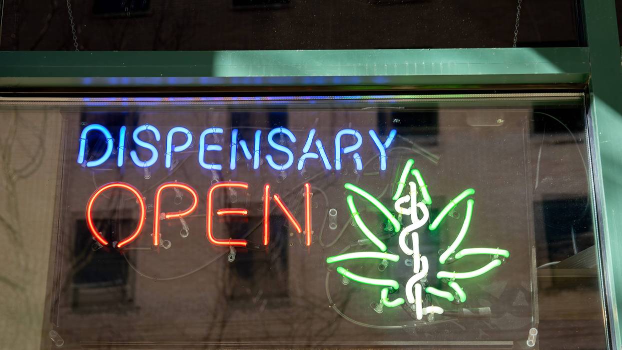 stock photo of neon sign that says 'dispensary open' with a weed leaf