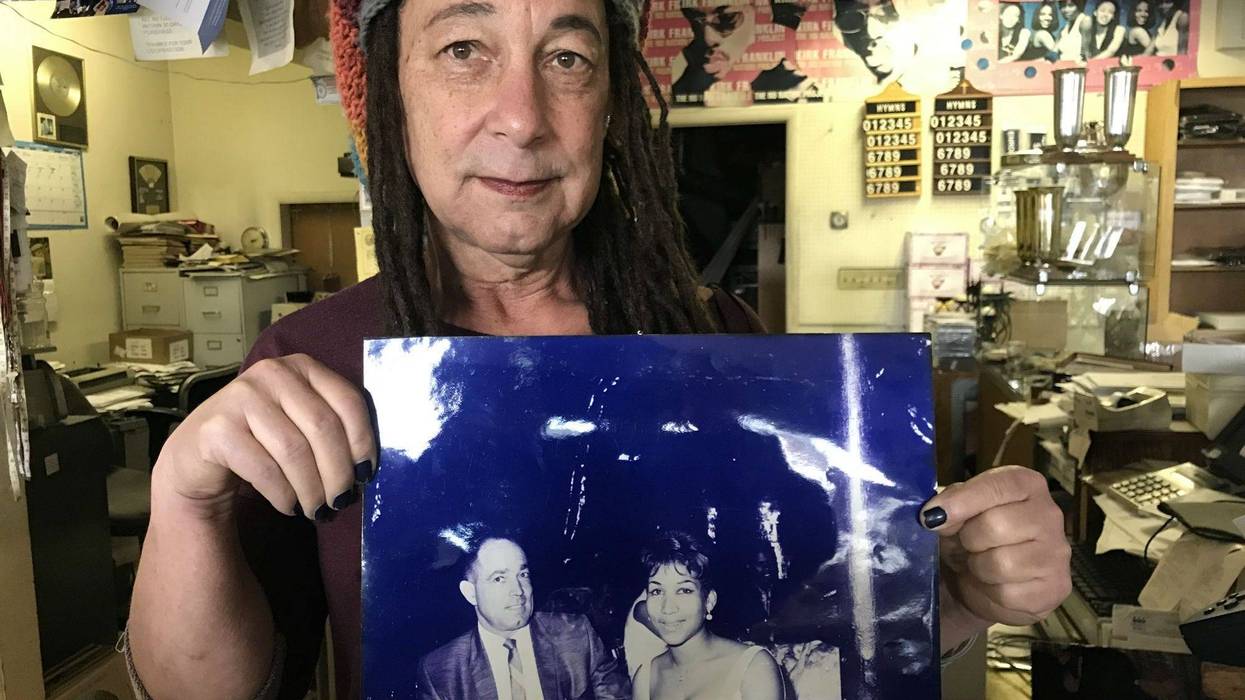 Store owner Diara Reid with a photo of her dad with then 17-year old Aretha Franklin, who he brought to Oakland for a gospel concert