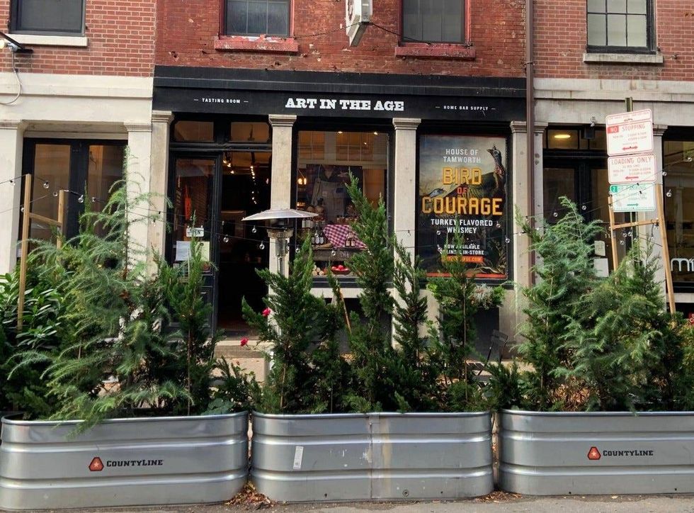 Storefront of Art in the Age, behind plant tubs.