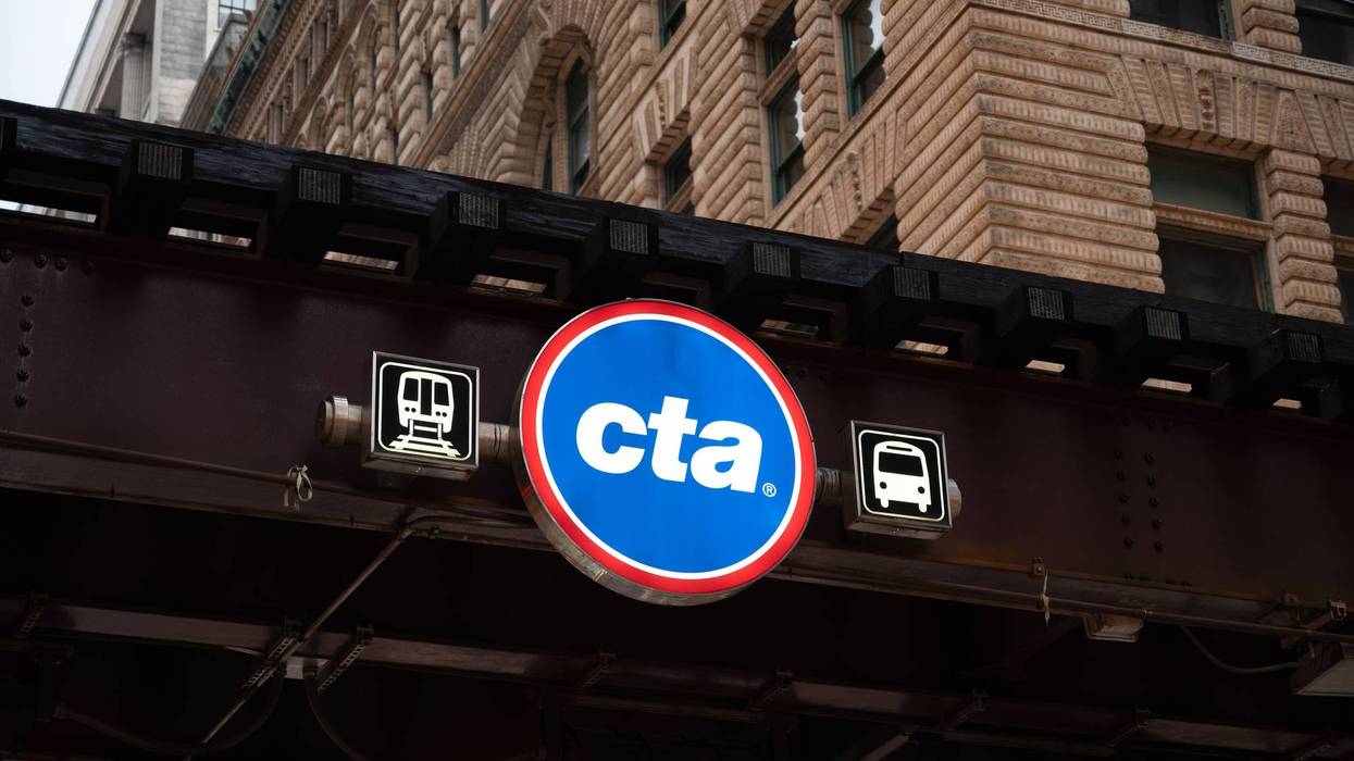Street sign of Chicago Transit Authority hanging over a bridge next to buildings
