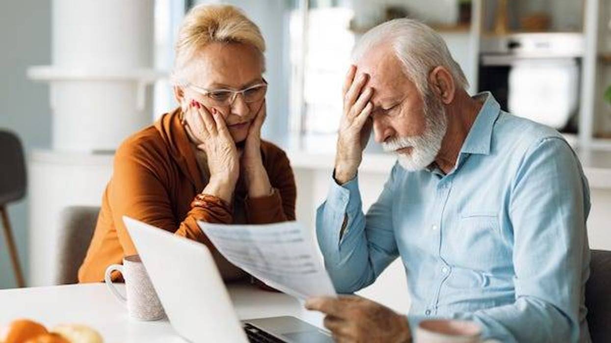 Stressed elderly couple looking over document at computer