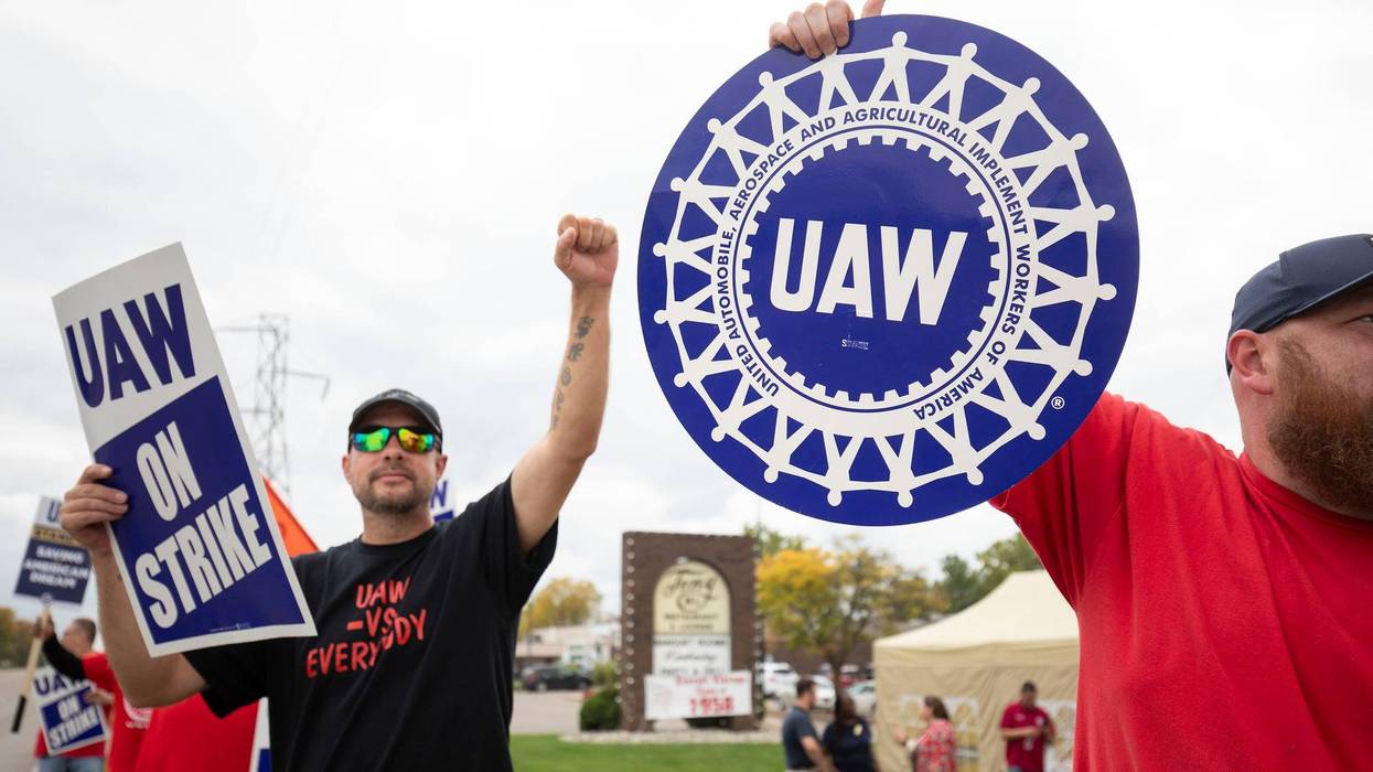 Striking UAW workers holding signs outside the General Motors Lansing Delta Assembly Plant on Friday.