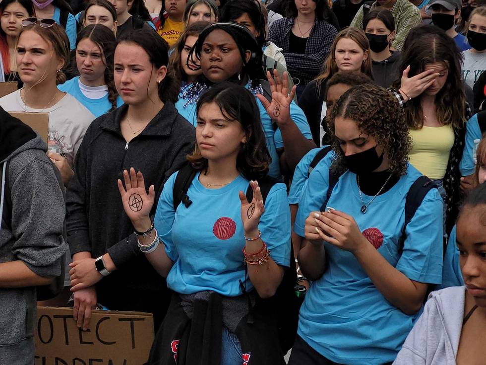 Students affected by gun violence raise hands during a May 2022 rally