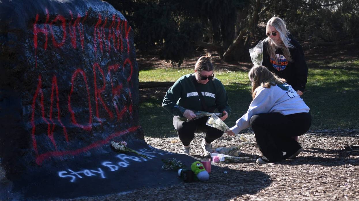 Students leave flowers at The Rock on MSU's campus following mass shooting