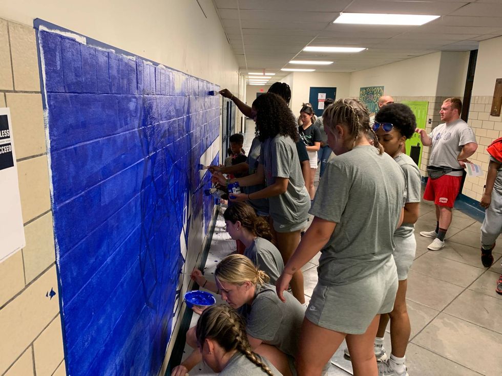 Students painting a mural in a high school hallway