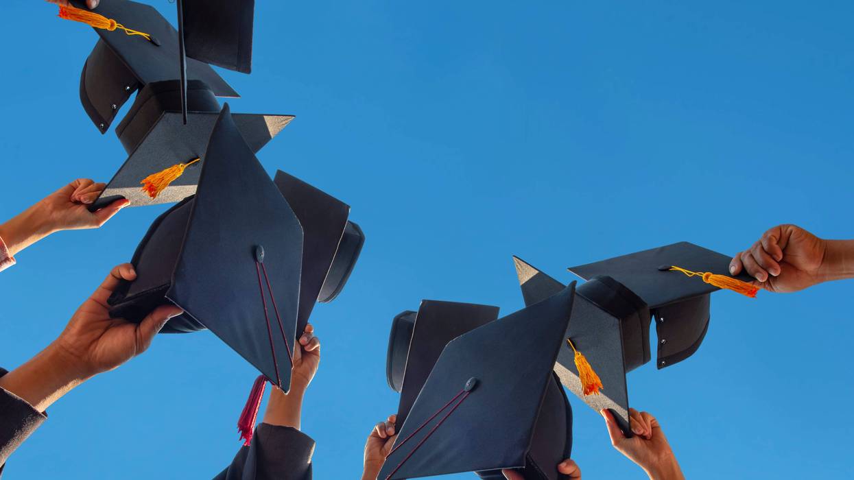 Students throw their caps in the air at a graduation ceremony
