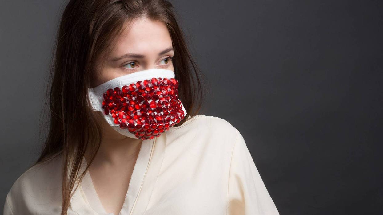 Studio portrait of Woman in protective mask with red rhinestones on a grey background