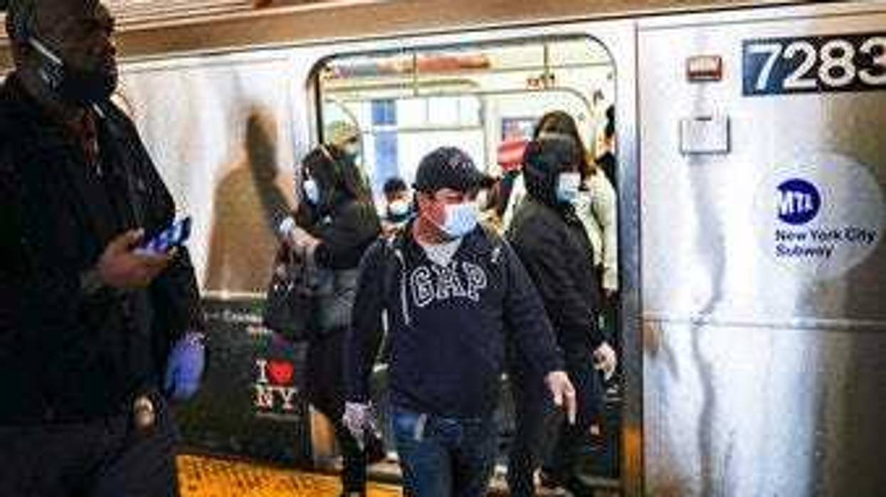 Subway riders, wearing personal protective equipment due to COVID-19 concerns, step off a train, Tuesday, April 7, 2020, in New York. (AP Photo/John Minchillo)
