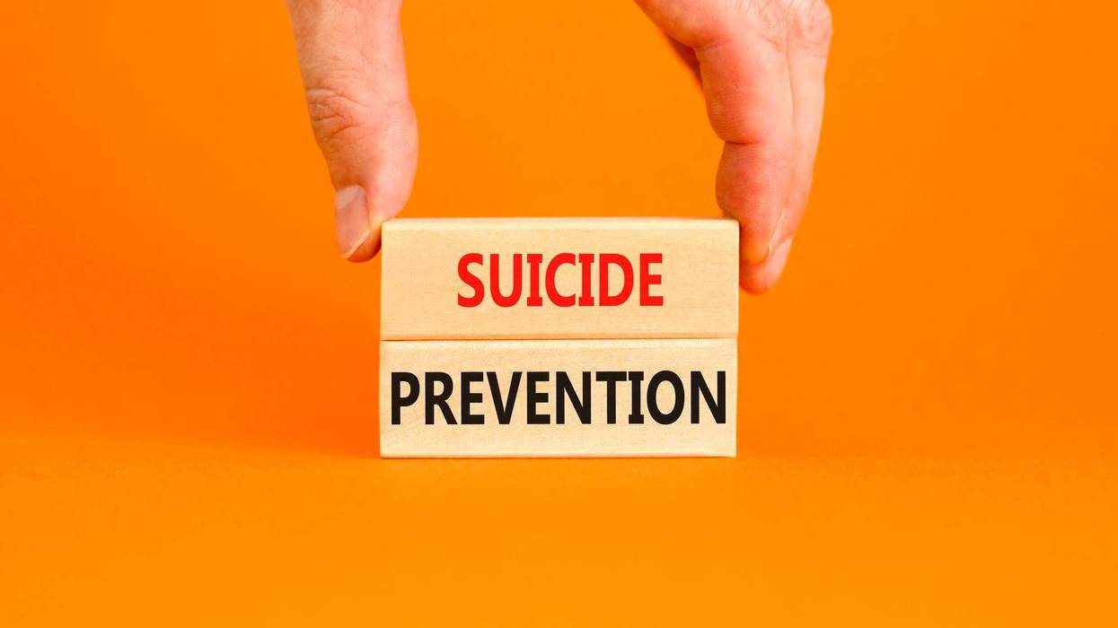 Suicide prevention written on blocks in front of an orange background. Stock photo.