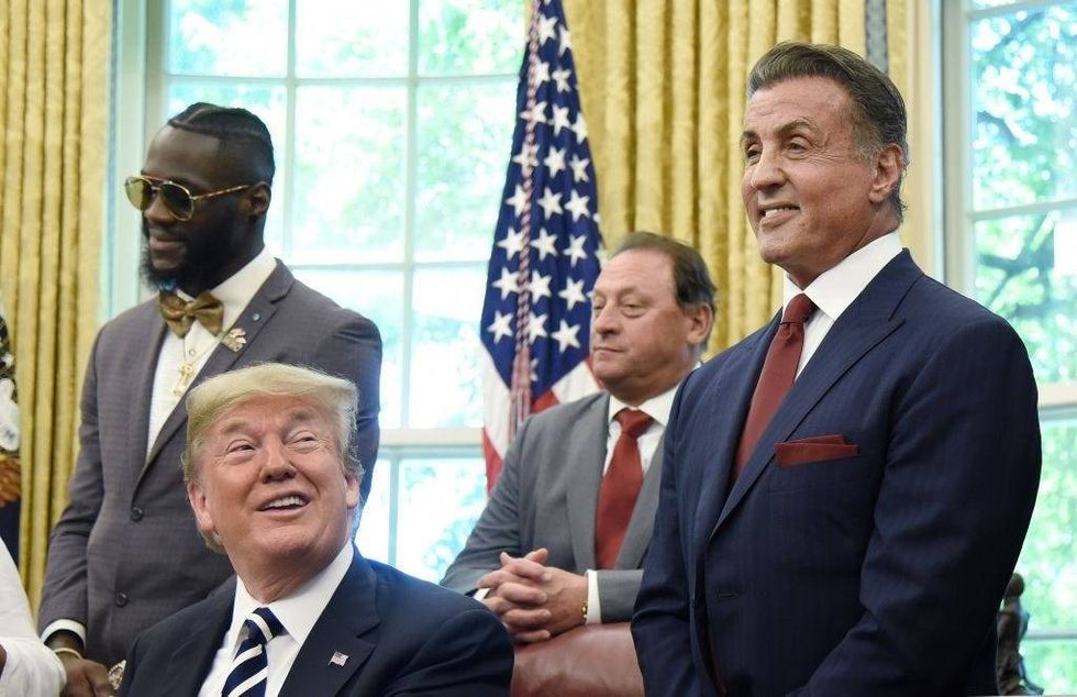 Sylvester Stallone (R) and President Donald Trump (L) share a laugh during a signing ceremony to grant posthumous pardon to former heavyweight champion Jack Johnson in the Oval Office of the White House on May 24, 2018 in Washington, DC.
