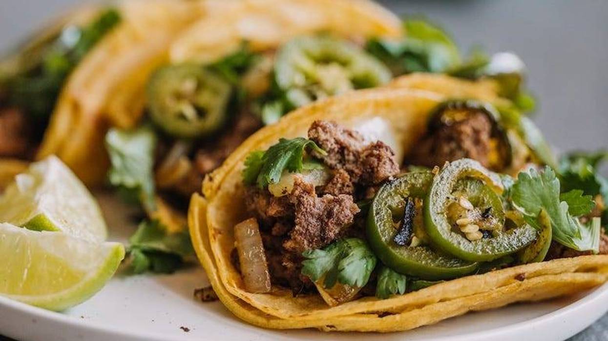 Tacos on a plate with fresh jalapeño, onion and cilantro