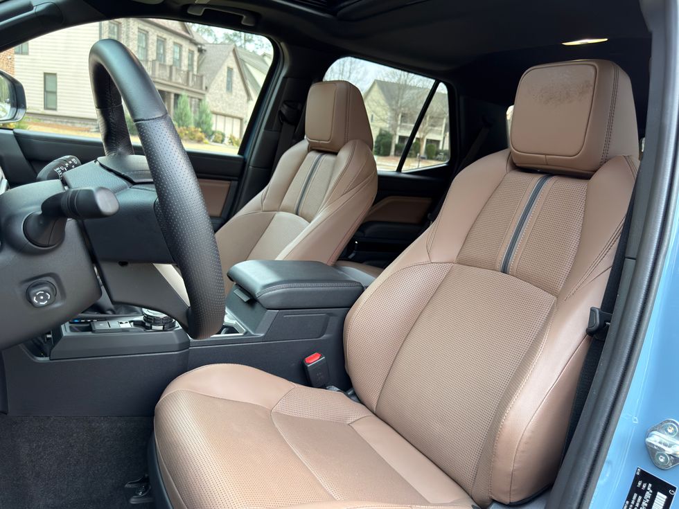 Tan perforated leather car interior with steering wheel, passenger seat, and center console.