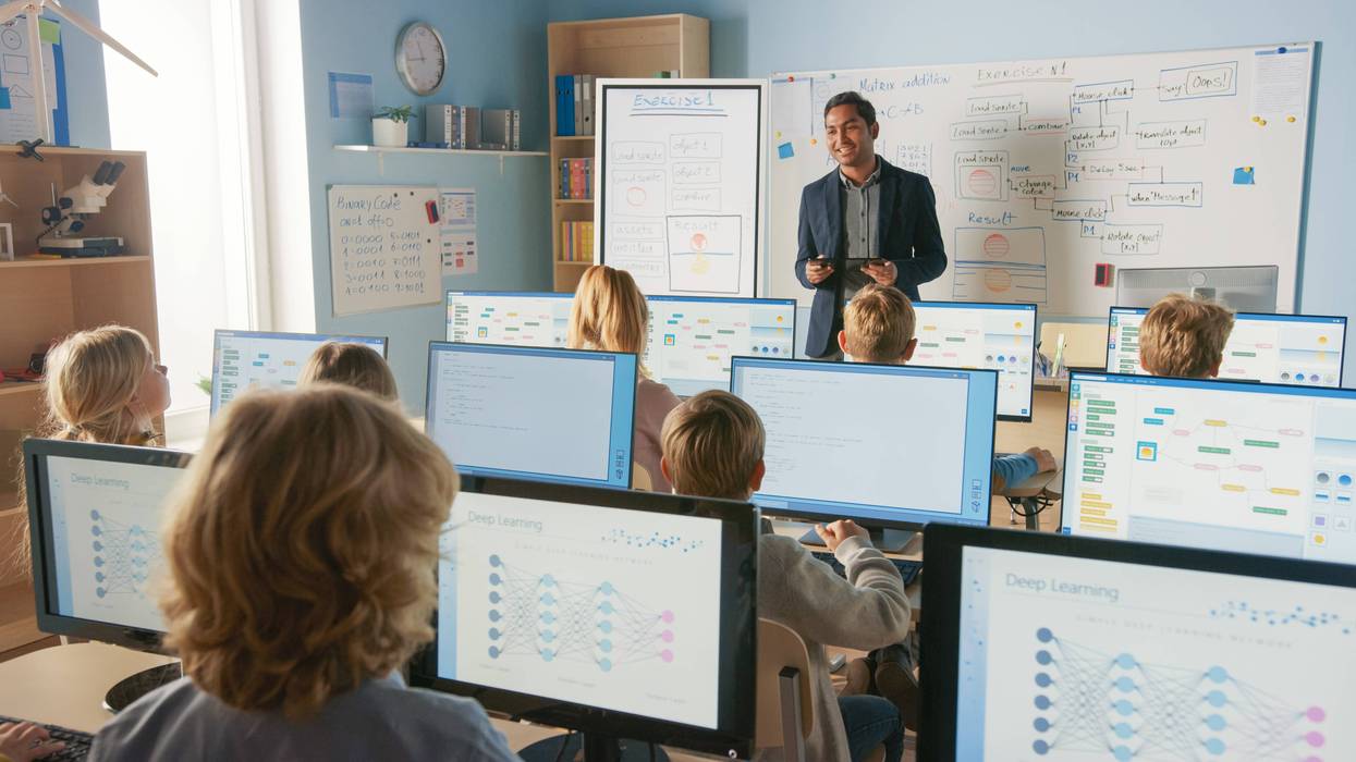 Teacher explains lesson to kids with computers