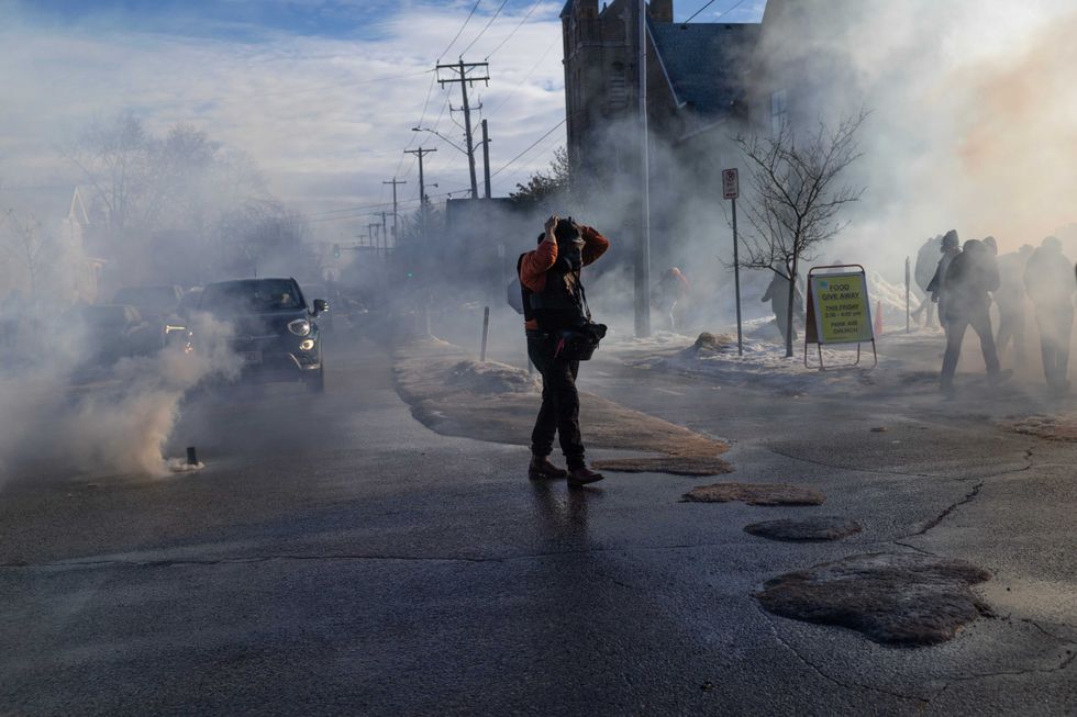 Tear gas tossed by federal immigration agents fills the air as agents clash with residents following a house raid on January 13, 2026 in Minneapolis, Minnesota.