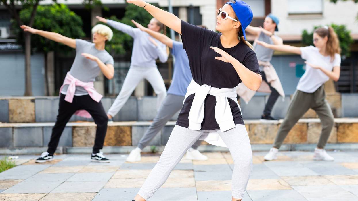 Teen girl street dancer performing with group outdoors