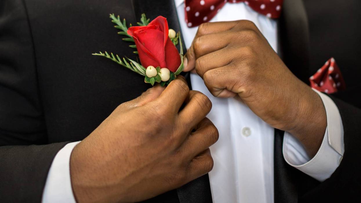 Teen pins his rose boutonniere to formal suit getting dressed and ready for prom