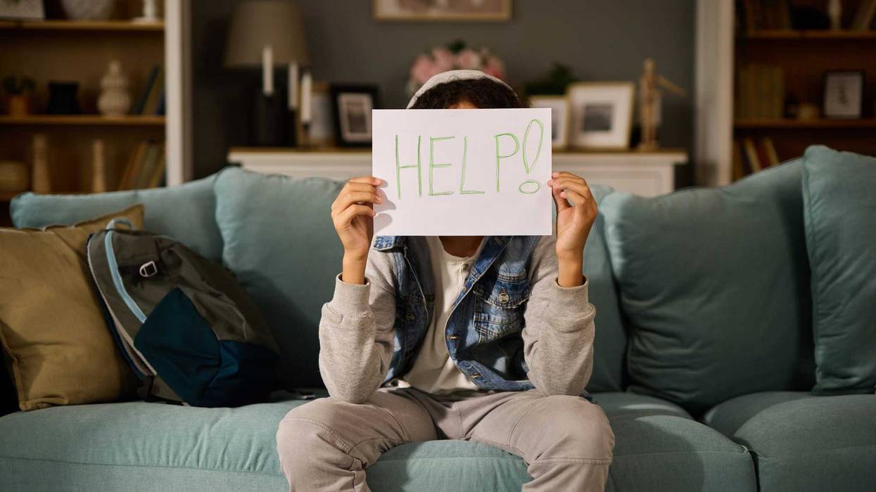 Teenage boy holding paper card with word Help