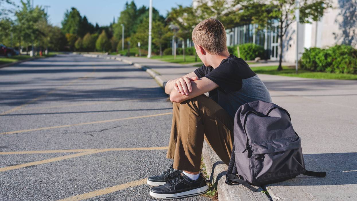 teenage boy sitting on curb