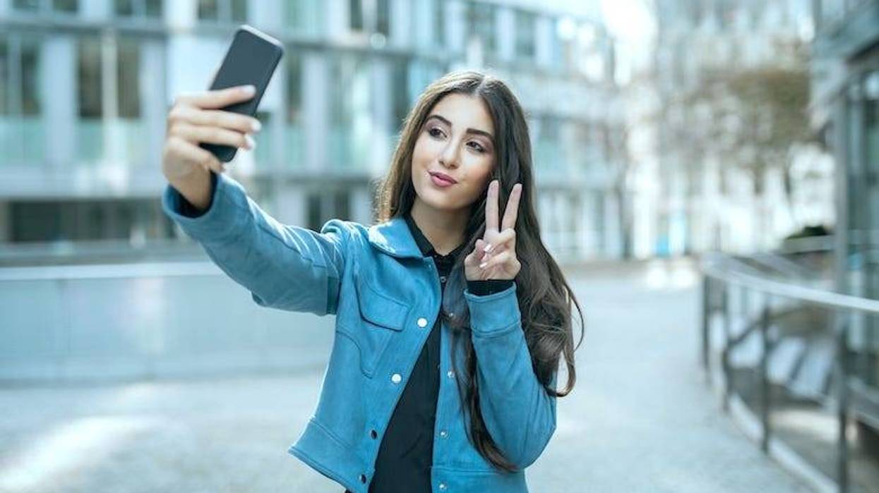 Teenage girl holding a peace sign taking a selfie
