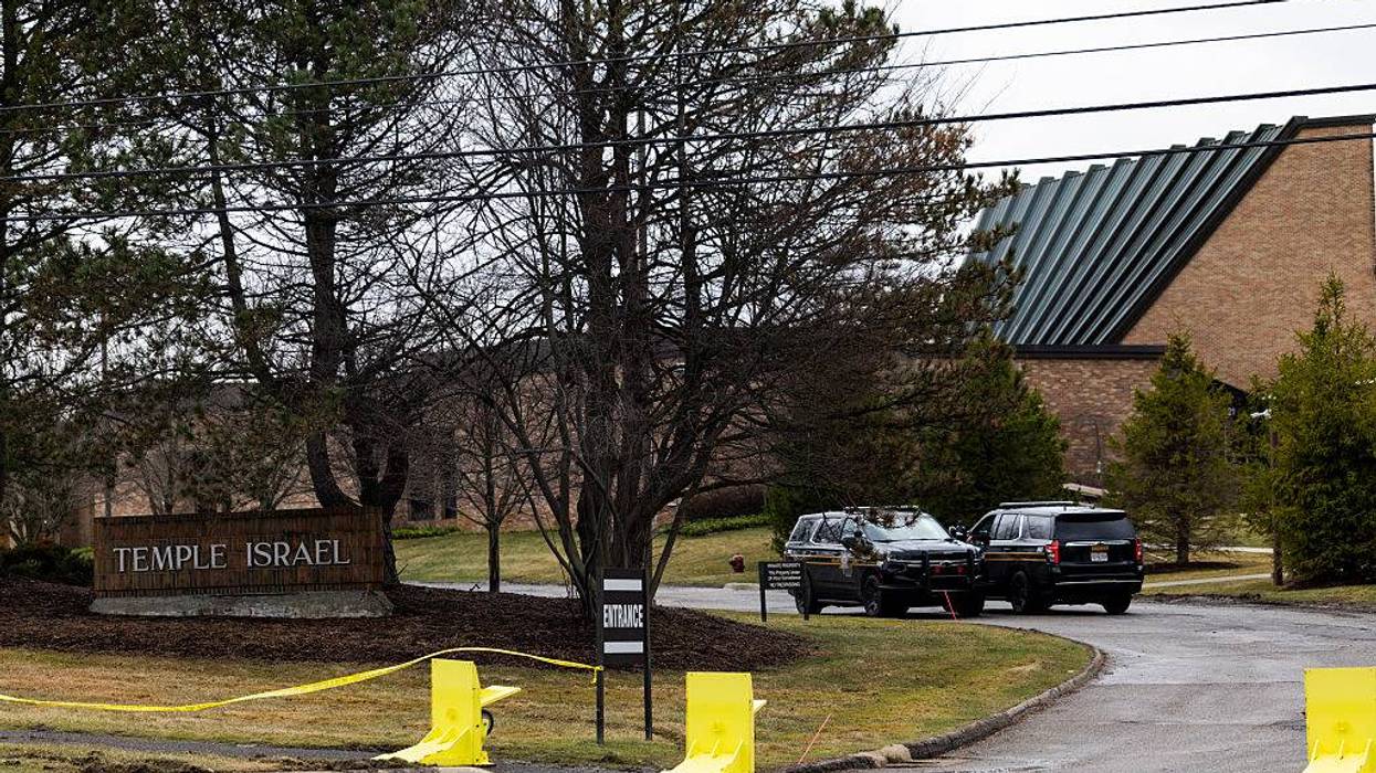 Temple Israel entrance with yellow caution tape, security barriers, and two police SUVs.