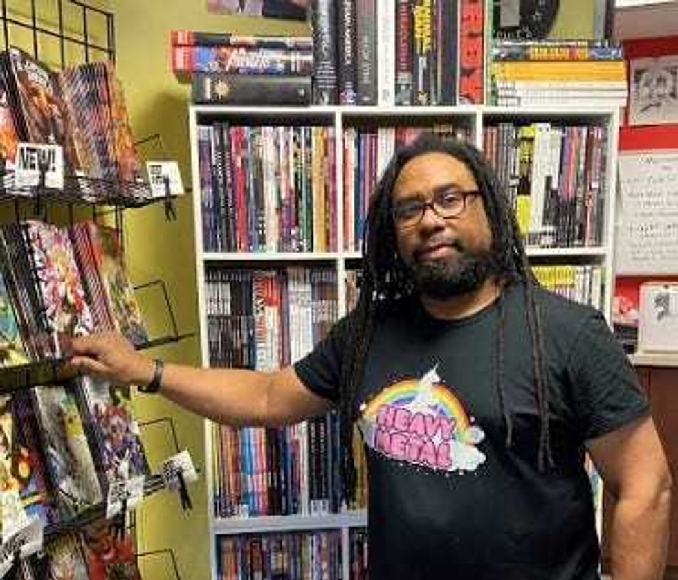 Terry Gant, owner of comic shop, next to shelves of comics
