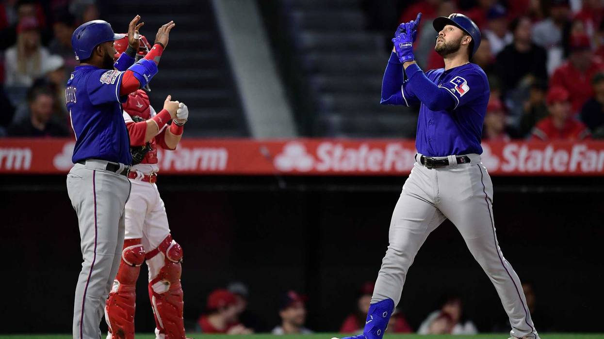 Texas Rangers' Joey Gallo, right, gestures as he scores after hitting a three-run home run as Elvis Andrus, left, waits to congratulate him and Los Angeles Angels catcher Jonathan Lucroy stands at the plate during the first inning of a baseball game Thurs