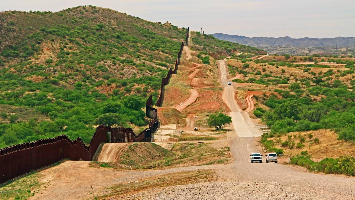 The border wall beside a road near Nogales, Arizona separating the United States from Mexico with border patrol vehicle