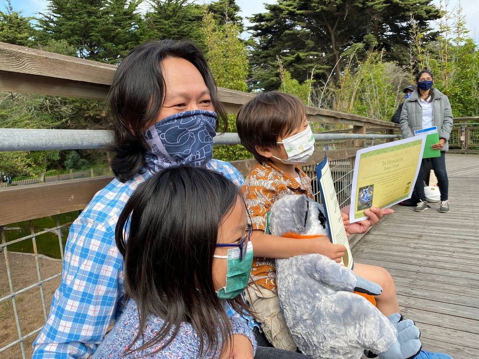 The boy who found Maki, the stolen lemur, and his father and sister relax at the San Francisco Zoo.