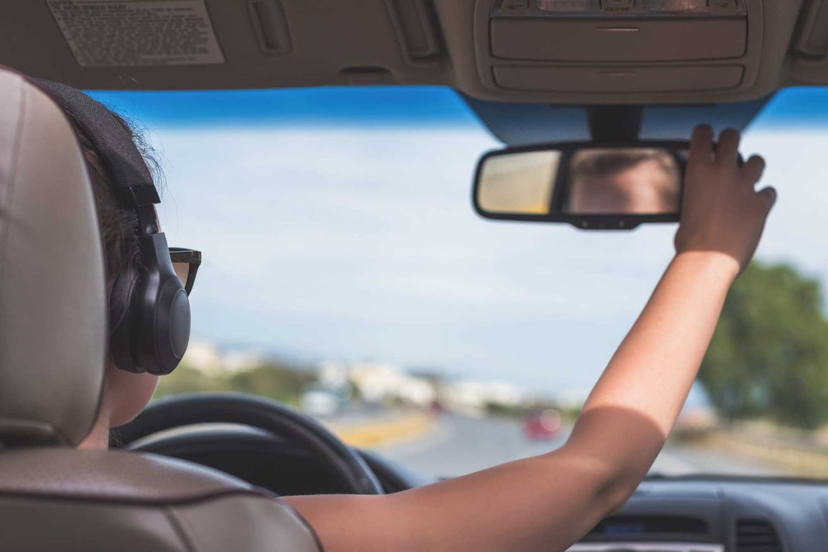 The girl in the headphones is driving on the highway in California. View from the back seat of the car on the windshield, road and the driver