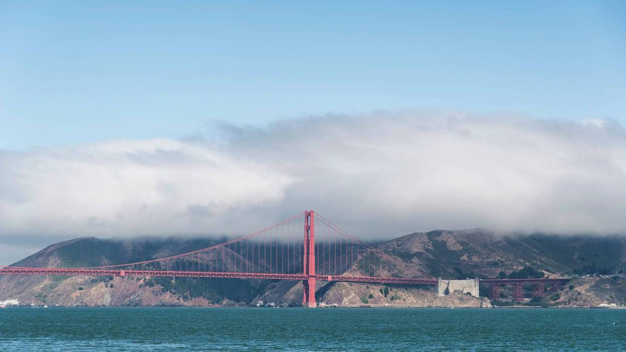 The Golden Gate Bridge on San Francisco Bay under a cloud of fog with the Marin Headlands in the background.