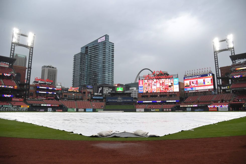 The infield is covered with a tarp cover as rain moves in before an opening-day baseball game between the St. Louis Cardinals and the Minnesota Twins, Thursday, March 27, 2025 in St. Louis.