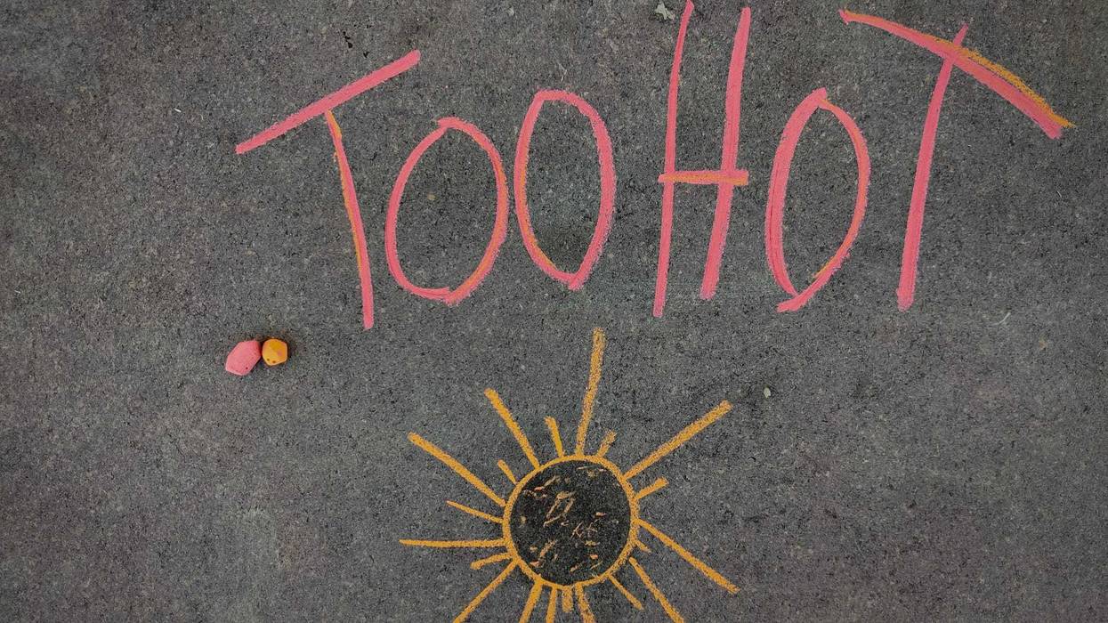 The inscription text on the grey board, Too hot with hand drawn sun. Using color chalk pieces.