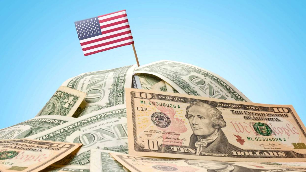The national flag of USA sticking in a pile of american dollars