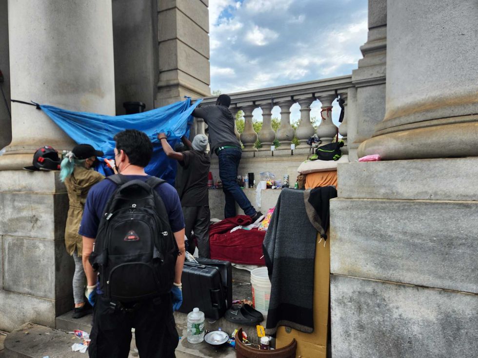 The same shelter halfway dismantled. A red blanket and sleeping mat were layed inside.