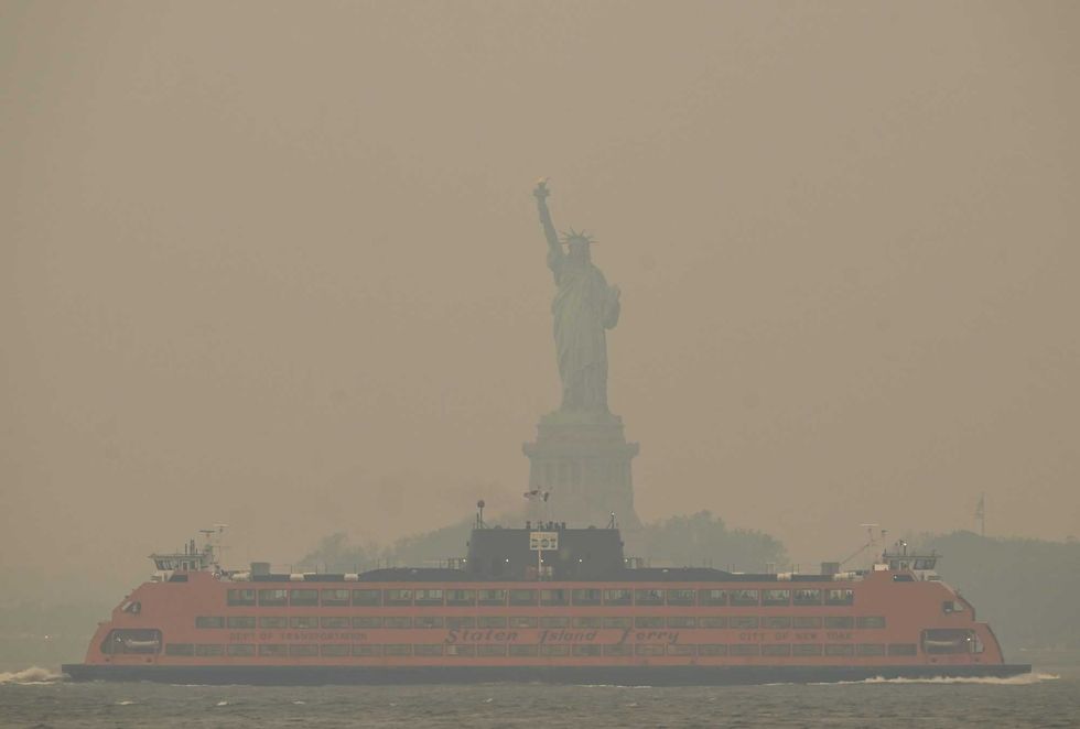 The Statue of Liberty stands shrouded in a reddish haze as a result of Canadian wildfires on June 6, 2023 in New York City
