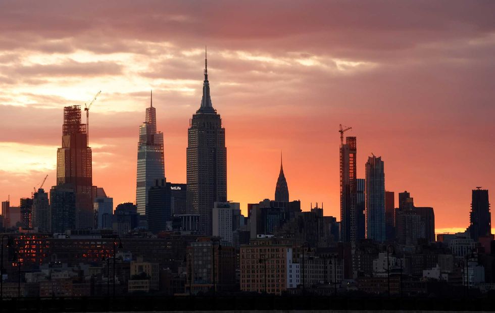 The sun rises behind the Empire State Building and Chrysler Building in New York City on June 24, 2024