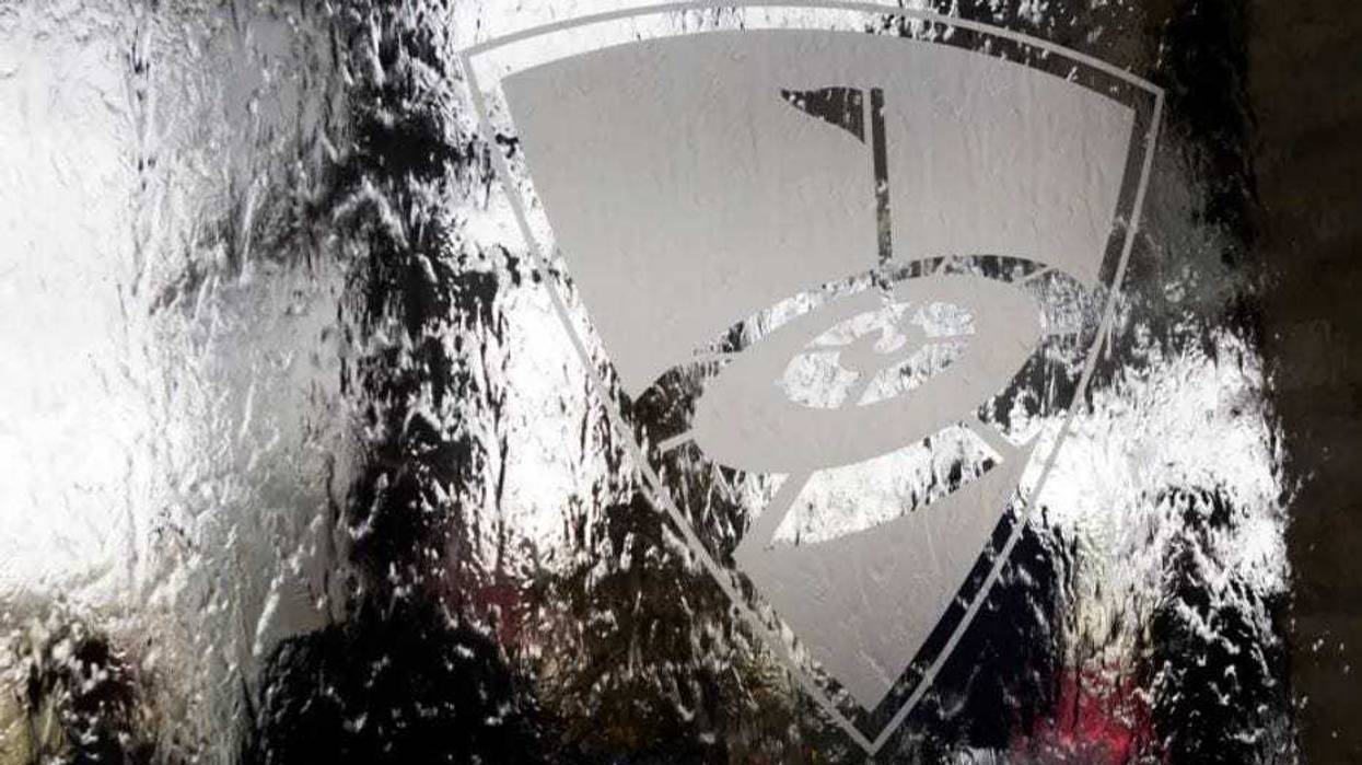 The TopGolf logo, seen from the back side of a glass water wall.