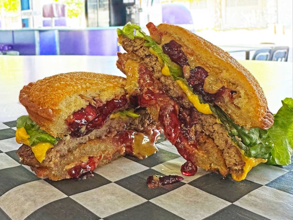 The "Uncrustaburger" - a 4 oz. hamburger patty with cheese, pickles and special sauce, sandwiched between two deep-fried peanut butter & grape jelly Uncrustables from Coasters.