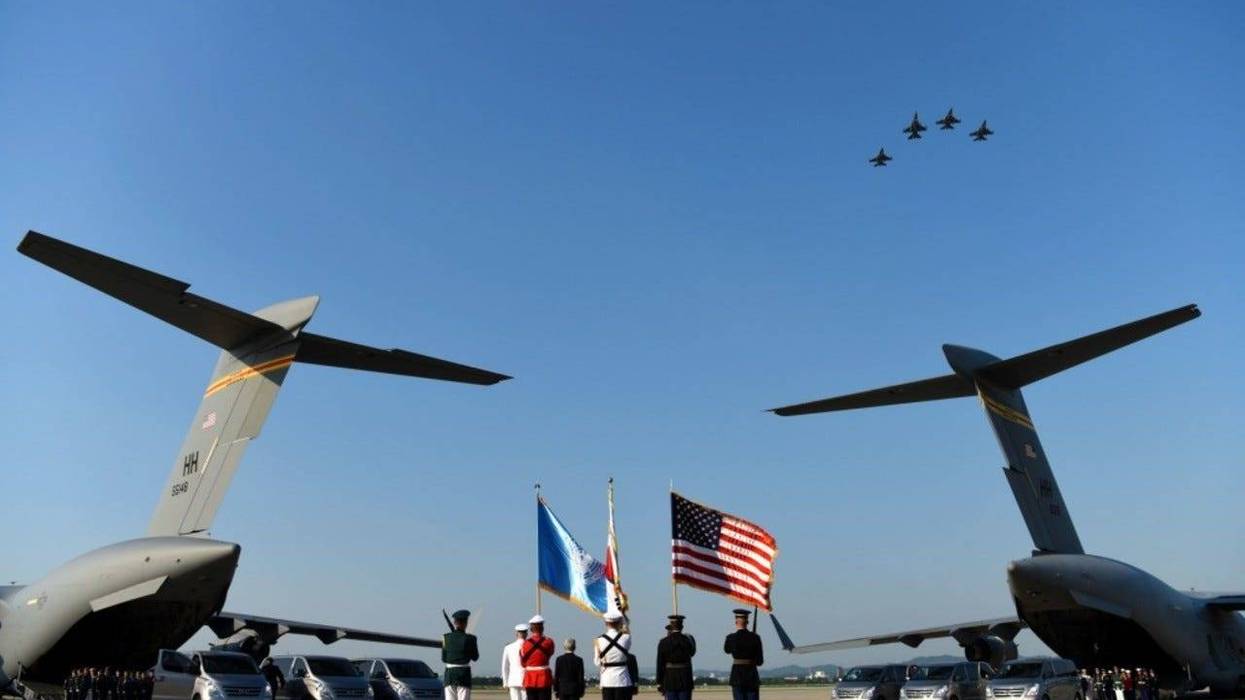 The United Nations Command Honor Guard prepares to transfer remains onto waiting C-17 Globemaster IIIs